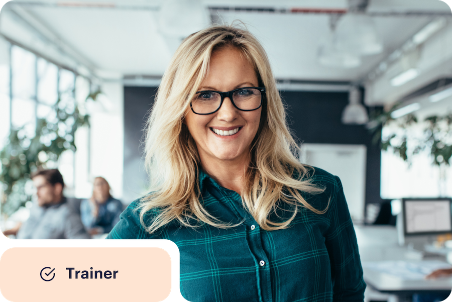 Woman in an office smiling with a circled checkmark next to the word trainer