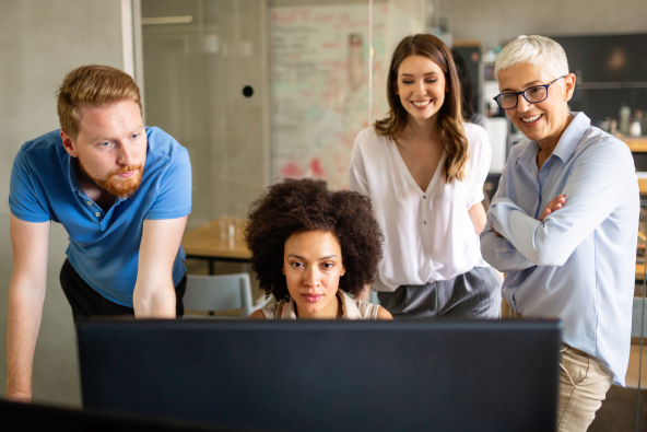 Four professionals working at a computer