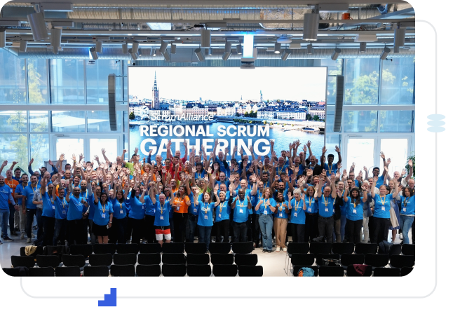 A Scrum Alliance Regional Scrum Gathering audience with their hands raised in celebration