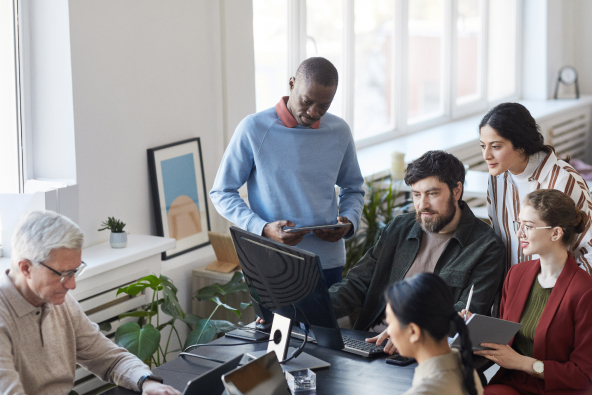 A group of colleagues gathered around a computer